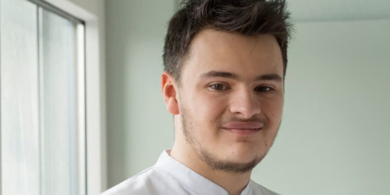 Portrait eines diplomierten Pflegefachmann in Ausbildung in Arbeitskleidung.