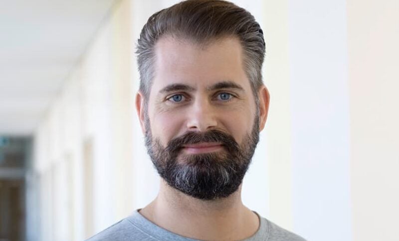 Portrait eines diplomierten Pflegefachmann HF mit Bart und blauen Augen.